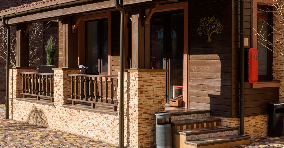 Beautiful wooden house exterior with stone accents and a cozy porch in bright daylight.